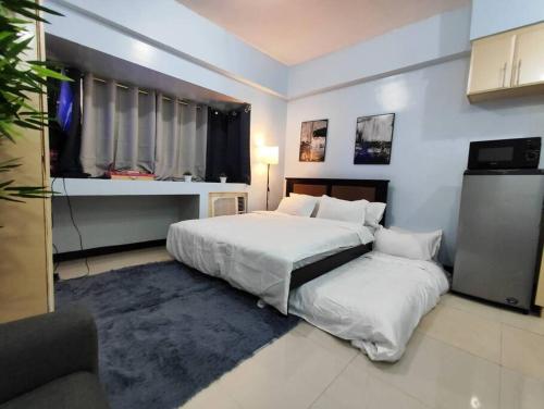 - une grande chambre avec 2 lits et une fenêtre dans l'établissement A2J Executive Studio Suite Near Venice Mall BGC, à Manille