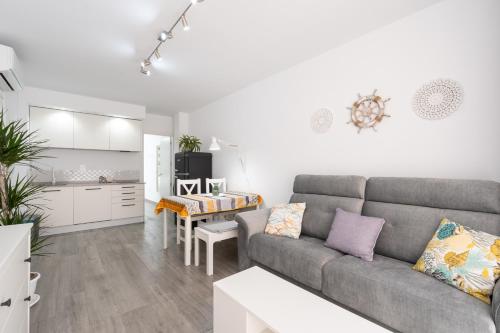 salon z szarą kanapą i kuchnią w obiekcie Apartamentos Joya del Mar w mieście Torre del Mar