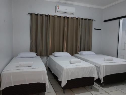 two twin beds in a room with curtains at Pousada Braga in Palmas