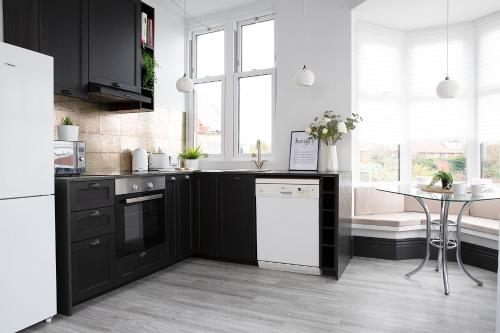 a kitchen with black and white appliances and a table at Beautiful first floor apartment in Poulton le Fylde