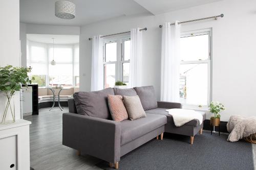 a gray couch in a living room with windows at Beautiful first floor apartment in Poulton le Fylde