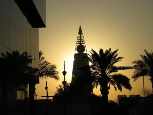 a building with a spire with palm trees in the foreground at Holiday Inn Olaya by IHG in Riyadh