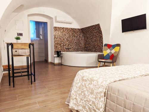 1 dormitorio con bañera, 1 cama y 1 silla en RAVI romantic jacuzzi suite, en Bari