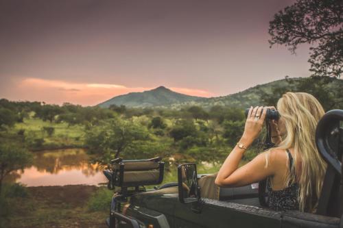 a woman sitting in the back of a jeep drinking from a bin at Leopard Mountain Safari Lodge in Manyoni Private Game Reserve