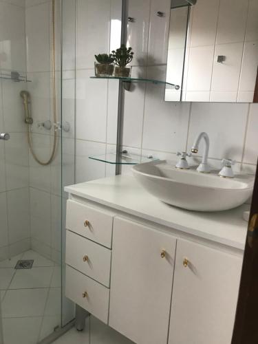 y baño blanco con lavabo y ducha. en Apartamento Vila Suzana, en Canela