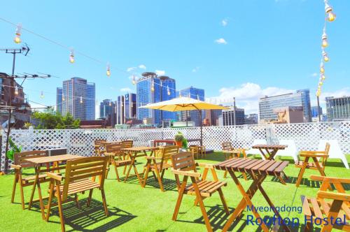 un grupo de mesas y sillas con una ciudad en el fondo en OYO Rooftop Hostel en Seúl