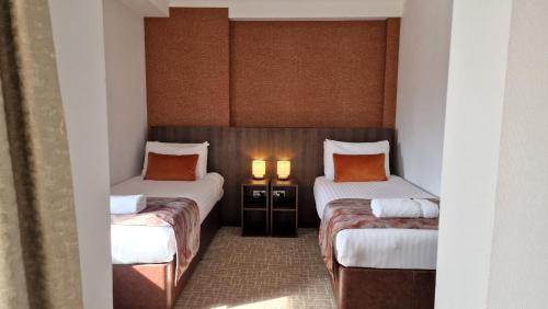 two twin beds in a room with two lamps at Coppid Beech in Bracknell