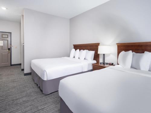two beds in a hotel room with white sheets at Country Inn & Suites by Radisson, Toledo, OH in Maumee