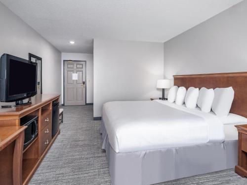 a hotel room with a bed and a flat screen tv at Country Inn & Suites by Radisson, Toledo, OH in Maumee