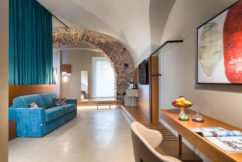 een woonkamer met een blauwe bank en een boog bij BASTIÒ PRIVATE SUITES in Catania