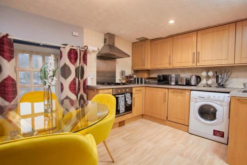 a kitchen with a glass table and yellow chairs at Perfect Place To Stay Fast Free WiFi in Edinburgh