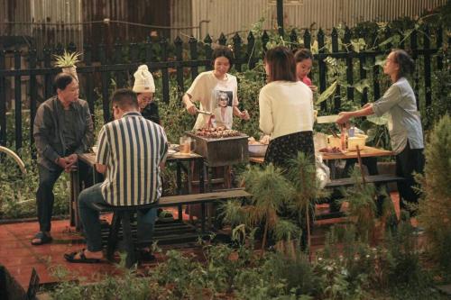 um grupo de pessoas em pé em torno de uma mesa em um jardim em Vuon An Villa - Best pine alley view, garden, BBQ em Ấp Ða Lợi