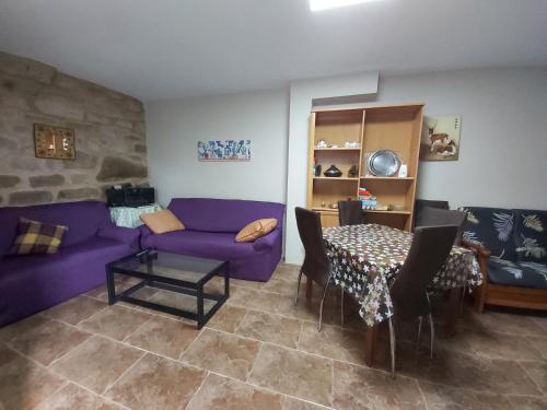 a living room with a purple couch and a table at Casa das Peleteiro Ribeira Sacra in Ourense