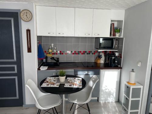 une cuisine avec des armoires blanches et une table et des chaises dans l'établissement Studio Montagnac, à Montagnac