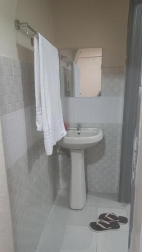 Baño blanco con lavabo y espejo en Woodgreek Studio Apartment 4B27, en Kisii