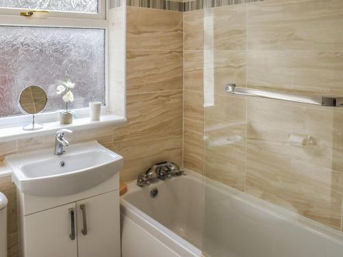 a bathroom with a sink and a tub and a shower at Montana Cottage in Happisburgh
