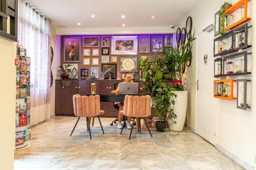 a woman sitting at a table in a room with a laptop at Hotel Ariane Montparnasse by Patrick Hayat in Paris