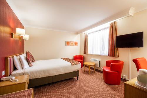 um quarto de hotel com uma cama e cadeiras vermelhas em Comfort Inn Arundel em Arundel