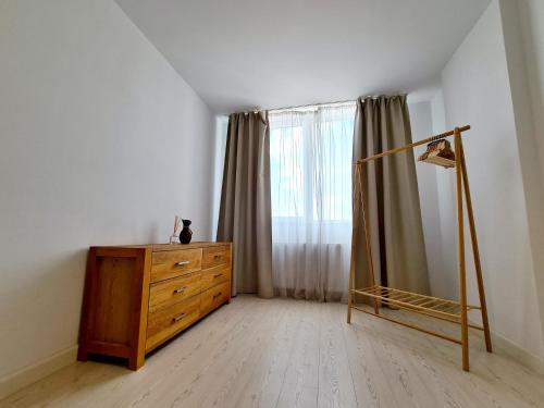 ein Schlafzimmer mit Kommode und Fenster mit Vorhängen in der Unterkunft CENTRAL Apartament Urbana in Arad
