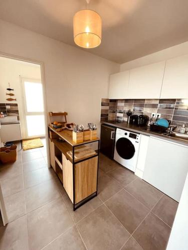 Il comprend une cuisine équipée d'une cuisinière et d'un lave-vaisselle blanc. dans l'établissement RAVISSANT T2 AVEC VUE MAGIQUE SUR L'ETANG DE THAU, à Balaruc-les-Bains