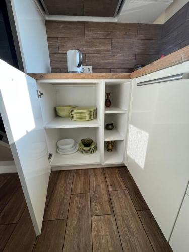 a kitchen with white cabinets and wooden floors at Holiday House Strawberry in Druskininkai