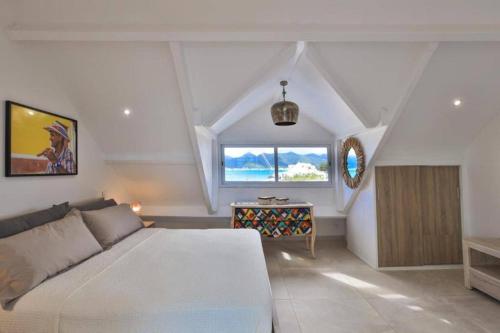 a bedroom with a white bed and a window at Villa Paradis Bleu Maison sur la plage, 2 chambres, piscines, tennis in Baie Nettle