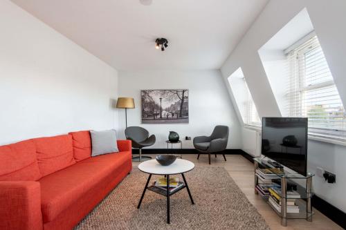 a living room with a red couch and a tv at Farringdon Penthouse Loft by City Living London in London