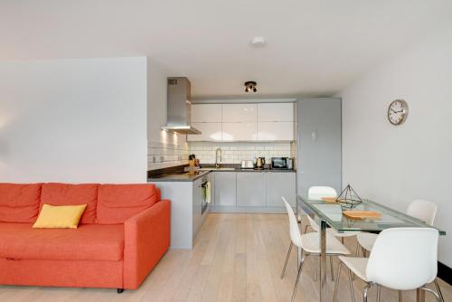 a living room and kitchen with a red couch and a table at Farringdon Penthouse Loft by City Living London in London