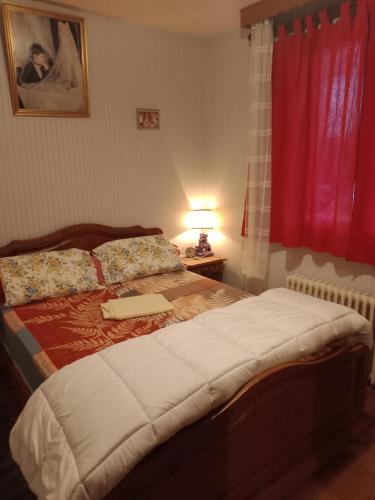 łóżko w sypialni z czerwoną zasłoną i oknem w obiekcie Maison entière Garage et parking w mieście Montluçon