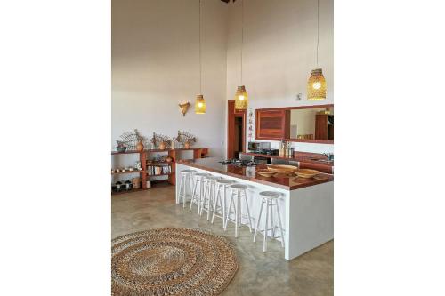 a kitchen with a counter and stools in a room at Villa Guaiuba linda casa com piscina e vista por mar ! in Icaraí