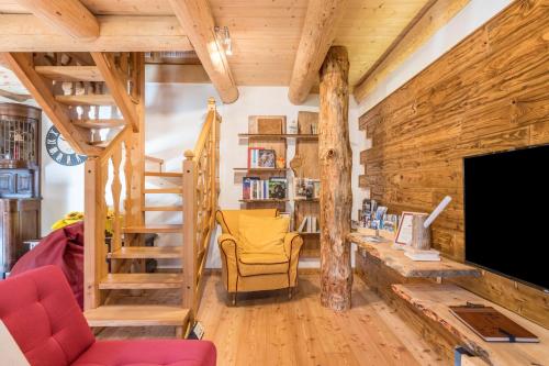 a living room with wooden walls and a staircase and a television at Baita Dani in San Martino di Castrozza