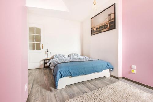 um quarto branco com uma cama com um cobertor azul em Le Brooklyn em Liévin
