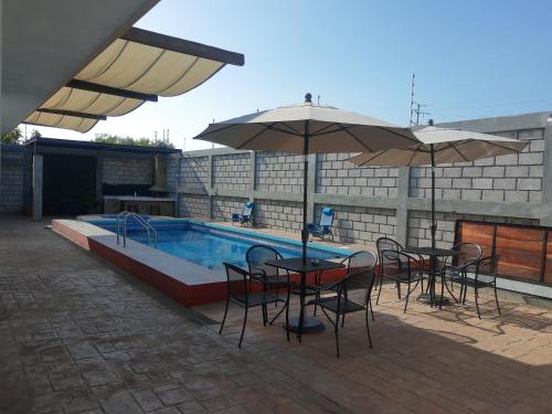uma piscina com mesas, cadeiras e guarda-sóis em HB Alebrijes SC em Lachiraguigú