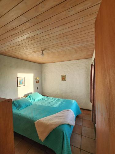 a bedroom with a green bed with a wooden ceiling at Cabañas Aloha-ki in El Quisco