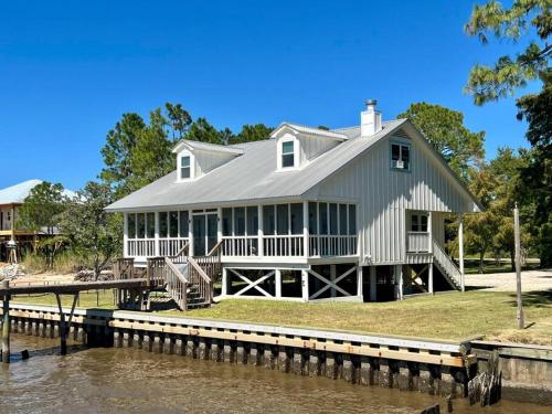 a large white house on a dock next to the water at Write on the Bay, a Waterfront Retreat in Coastal Alabama in Fairhope