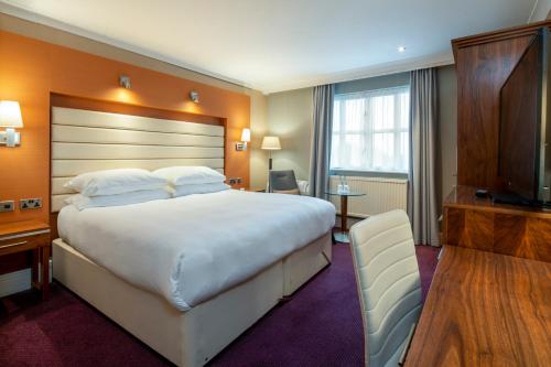 um quarto de hotel com uma cama grande e uma televisão de ecrã plano em The Telford Hotel, Spa & Golf Resort em Telford