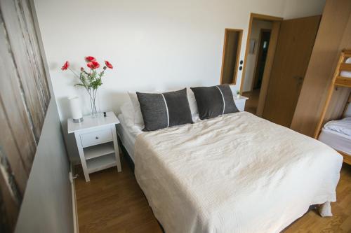 um quarto com uma cama e uma mesa com um vaso de flores em Guesthouse Lyngholt em Þórshöfn