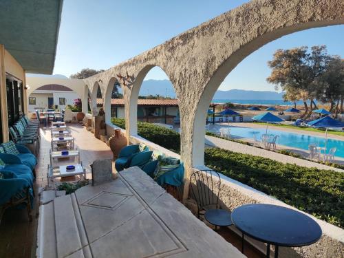 um pátio com mesas e cadeiras ao lado de uma piscina em Hotel Tsagarakis Beach em Amoudara Herakliou