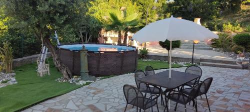 una mesa con sillas y una sombrilla junto a la piscina en Villa cassandra, en Maratea