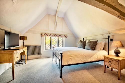 a bedroom with a bed and a desk and a television at The Woolpack Inn in Coggeshall