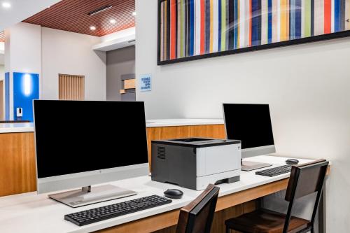 a desk with two computer monitors and a printer at Holiday Inn Express & Suites - Lincoln Downtown by IHG in Lincoln