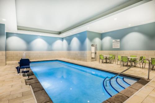 a swimming pool with tables and chairs in a room at Holiday Inn Express & Suites - Lincoln Downtown by IHG in Lincoln
