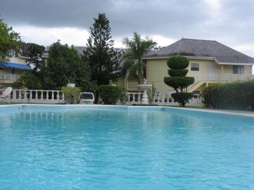 a large blue swimming pool in front of a house at Stylish studio apt AC, Balcony, Parking, Pool in Ocho Rios