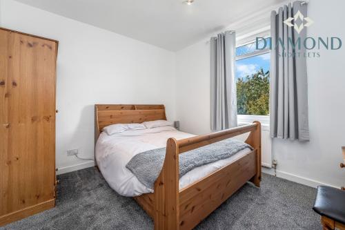 - une chambre avec un lit en bois et une fenêtre dans l'établissement Cosy 2 Bed Apt West End Edinburgh FREE PARKING, à Édimbourg