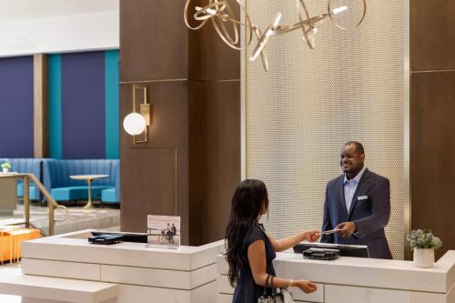 a man and a woman standing at a counter in a lobby at Crowne Plaza College Park - Washington DC by IHG in Greenbelt