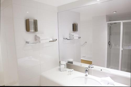 a white bathroom with a sink and a shower at Louis Fitzgerald Hotel in Clondalkin