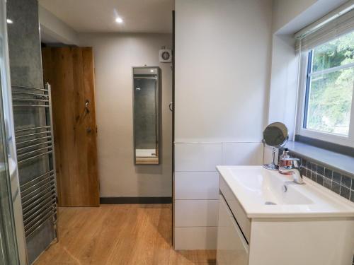 La salle de bains blanche est pourvue d'un lavabo et d'une douche. dans l'établissement Yon Cottage, à York