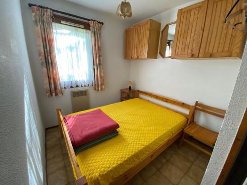 - une petite chambre avec un lit jaune et une fenêtre dans l'établissement Charmant 2 pièces avec balcon, parking, proche des pistes - La Clusaz - FR-1-459-34, à La Clusaz