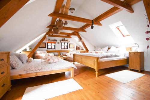 a attic bedroom with two beds and wooden floors at U Kopejdy in Smržovka