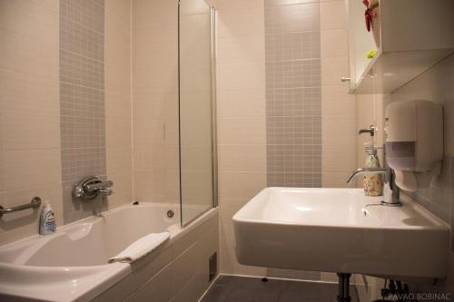 een badkamer met een bad, een wastafel en een douche bij Nova galerija Ema in Zagreb